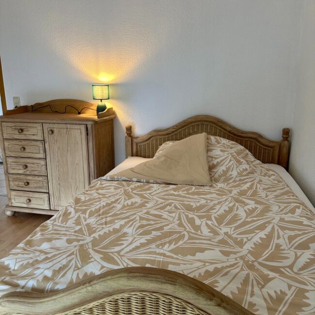 Ein Bett und ein Nachttisch in einem Zimmer des betreuten Wohnens von Neue Wege.