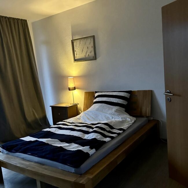 Ein Bett und ein Nachttisch in einem Zimmer des betreuten Wohnens von Neue Wege.