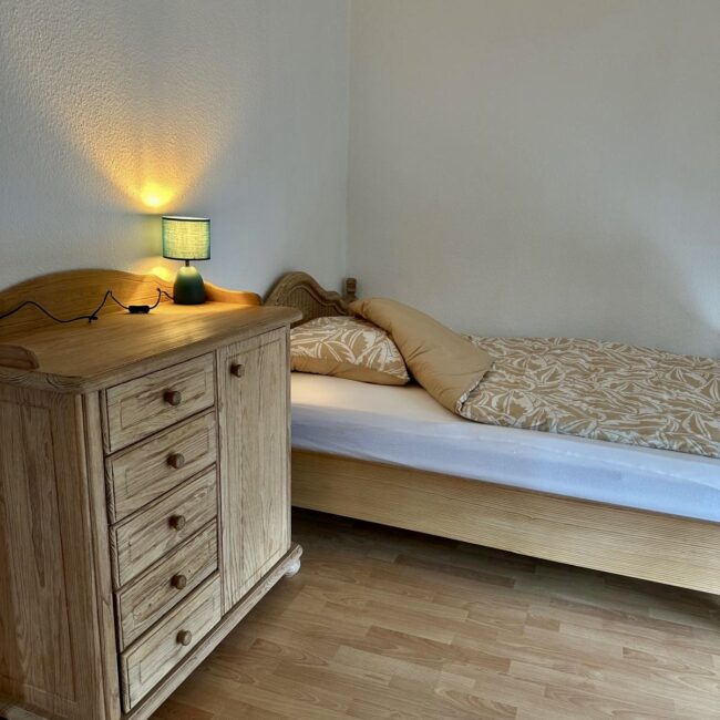 Ein Bett und ein Nachttisch in einem Zimmer des betreuten Wohnens von Neue Wege.